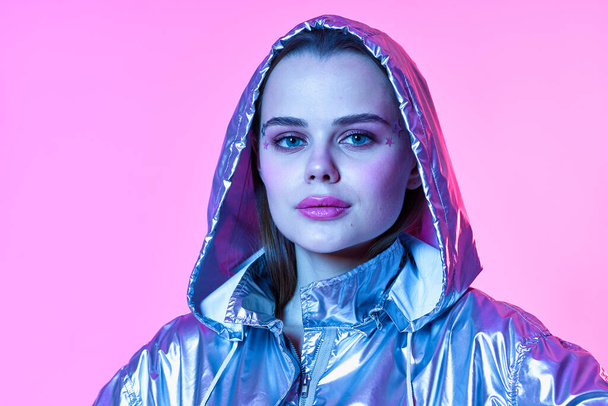 attractive woman silver hooded jacket makeup pink background neon - Photo, Image