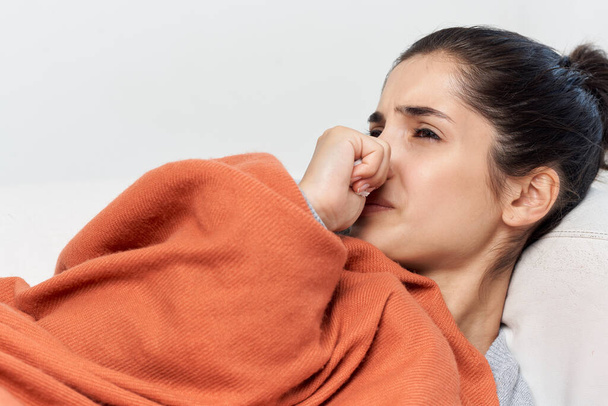 不健康な女性は毛布で覆われたソファの上に横たわっています健康上の問題 - 写真・画像