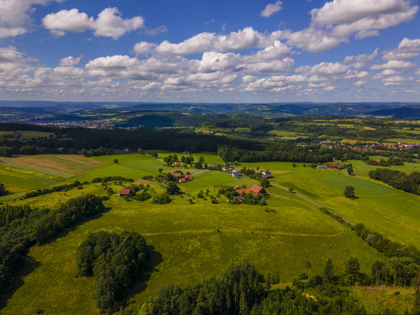 An aerial view of the cloudy sky over the green agricultural fields and ruralhouses - Fotó, kép