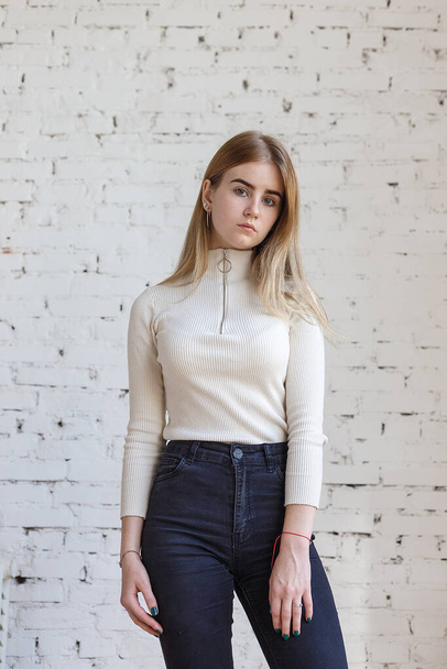 portret van jonge bedachtzame tiener model dragen witte trui en zwarte jeans - Foto, afbeelding