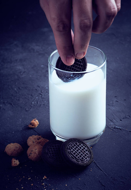 Een verticaal shot van koekjes en een glas melk op een blauwe achtergrond - Foto, afbeelding
