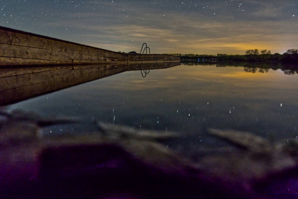 A mesmerizing view of the starry sky over the Oberrieder Weiher, Bayern, Germany at night - 写真・画像