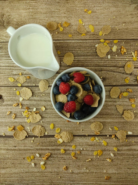 A top view of a bowl of fresh and delicious Granola and milk on a wooden table - Foto, afbeelding