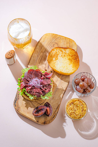 Hamburger au pastrami tranché servi avec de la laitue sur un pain de sésame fraîchement cuit sur fond blanc - Photo, image