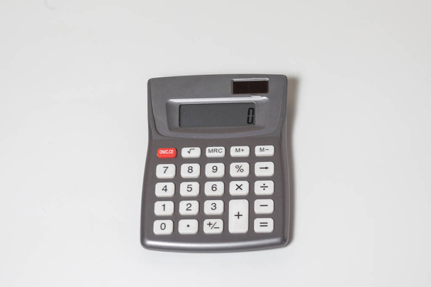 A plastic calculator on a white surface displaying a zero - Foto, Imagen
