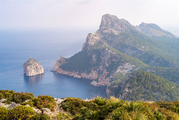 A Mesmerizing view of green mountains in the ocean under light sky on a summer day in Mallorca, Spain - Fotoğraf, Görsel