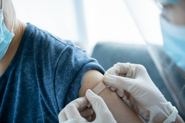 El médico prepara una dosis de vacuna inyectable en el brazo izquierdo del paciente de cerca con espacio para copias. Concepto de salud y servicio médico. COVID-19 o vacuna para la cura del coronavirus inyectable. - Foto, Imagen
