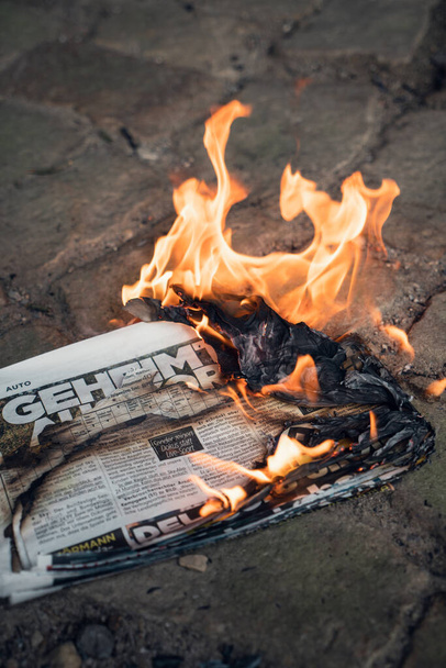 WALSRODE, GERMANY - Mar 17, 2020: A vertical shot of a burning BILD Zeitung newspaper on the ground - 写真・画像
