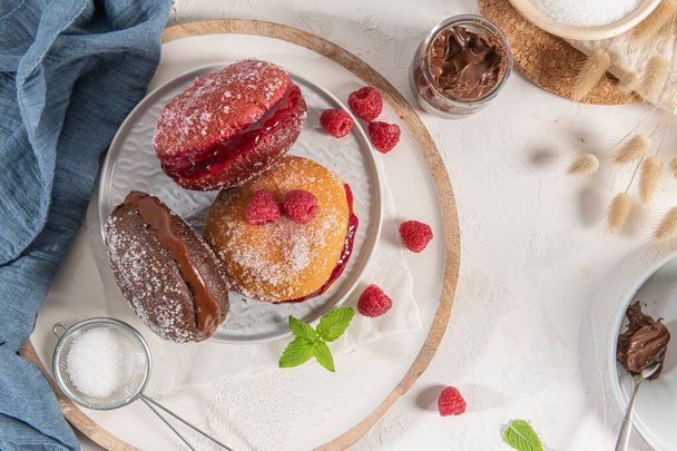 Bolas de Berlim, or "Berlin Balls". Portuguese fried dough with sugar, Filled with chocolate or raspberry jam. Portuguese fried dough with sugar. Chocolate and  beetroot  berliner Pancakes Doughnuts Donuts stuffed with various creams - Photo, Image