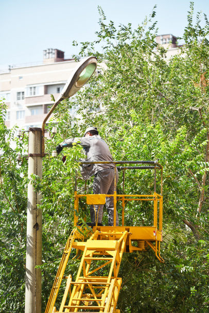 Un trabajador de la plataforma aérea cambia una lámpara en una lámpara de calle - Foto, Imagen