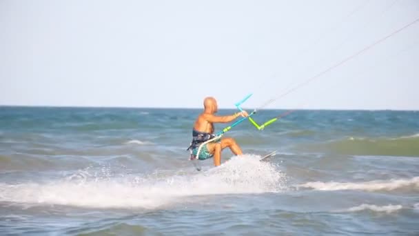 Kafkas formundaki genç erkek uçurtma sörf tahtası sürmekten hoşlanır. Deniz ya da okyanus kıyısında mavi gökyüzüne karşı son derece parlak, güneşli bir günde müthiş bir numara yapar. Watersport adrenalin eğlence macera keskinliği - Video, Çekim