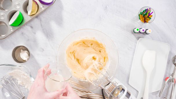 Flat lay. Step by step. Mixing ingredient in a mixing bowl with an electric mixer to bake vanilla Mardi Gras cupcakes. - Photo, image