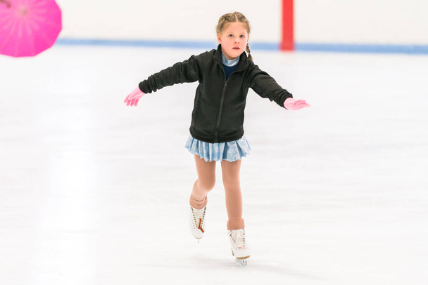 Klein meisje oefenen kunstschaatsen op een indoor schaatsbaan. - Foto, afbeelding