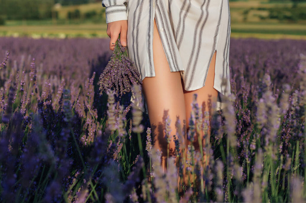 Young woman with lavender bouquet on violet flowers field background - Foto, afbeelding