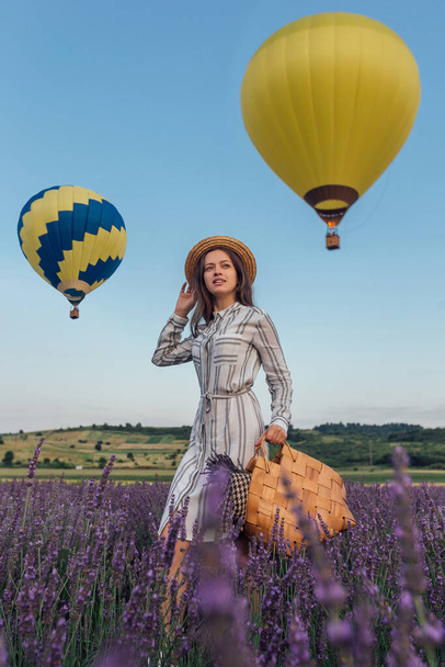 Young woman with lavender bouquet basket on sky aerostats background - Foto, afbeelding