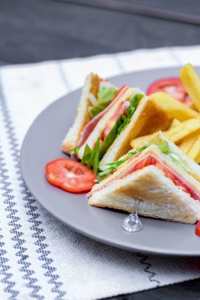 Klubový sendvič, 4 plátky na šedém talíři s rajčaty a hranolky - Fotografie, Obrázek