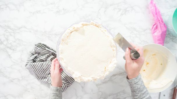 Plat gelegd. Stap voor stap. Frosting ronde funfetti cake met witte Italiaanse boterroom glazuur. - Foto, afbeelding