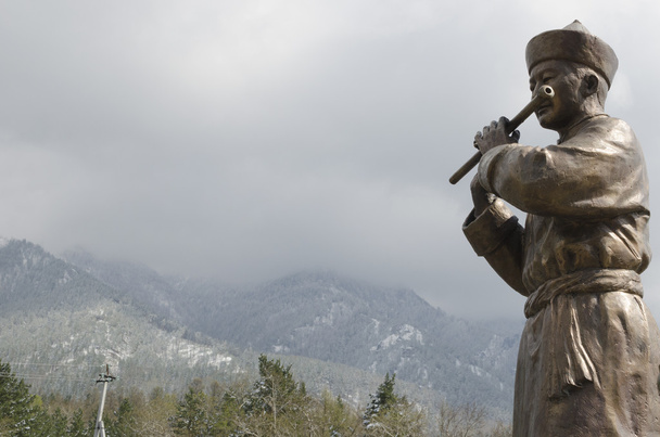 Sculpture of a man in the Buryat national dress with flute on the bridge over Kyngyrga river in Arshan before flooding - Photo, Image