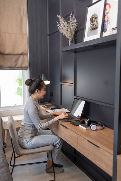 Arbeit von zu Hause aus Konzept ein junges Mädchen mit einem Dutt Haar macht ihre Remote-Arbeit in ihrem Schlafzimmer.  - Foto, Bild