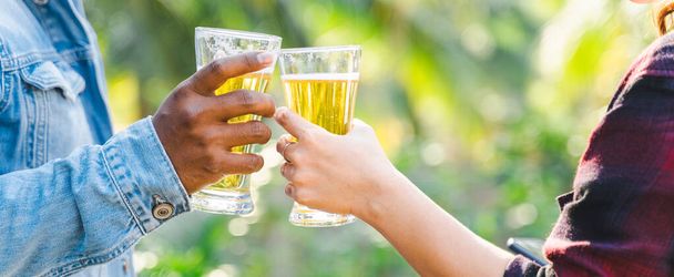 Cropped shot of people holding beer glasses celebrating in the summer camping party outdoor. Friends clinking bottle of beer during camping outdoor - Foto, imagen