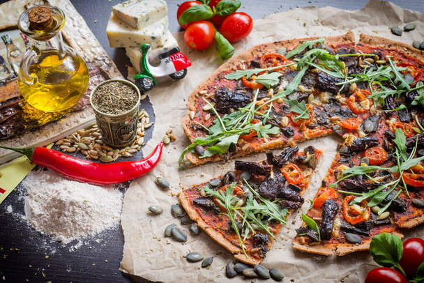 Dinkelteigpizza mit sonnengetrockneten Tomaten. Italienische Lebensmittel - Foto, Bild
