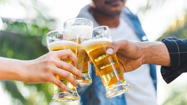 Cropped shot of people holding beer glasses celebrating in the summer camping party outdoor. Friends clinking bottle of beer during camping outdoor - Foto, Imagen