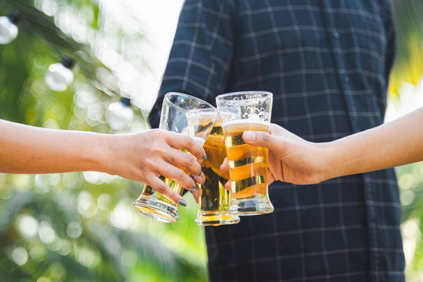 Обрезанный снимок людей, держащих пивные бокалы, празднующих летний кемпинг на открытом воздухе. Друзья звонят бутылку пива во время кемпинга на открытом воздухе - Фото, изображение