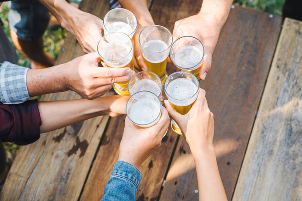 Plan recadré de personnes tenant des verres à bière célébrant dans la fête de camping d'été en plein air. Amis clinking bouteille de bière pendant le camping en plein air - Photo, image