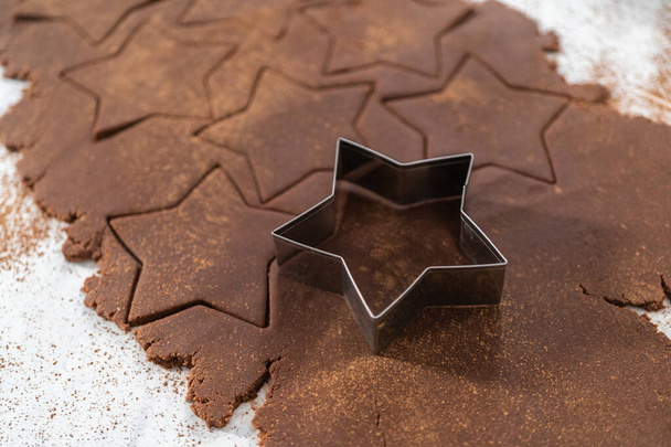 Kurabiye kesiciyle hamurdan yıldız şeklinde çikolatalı kraker kesmek.. - Fotoğraf, Görsel