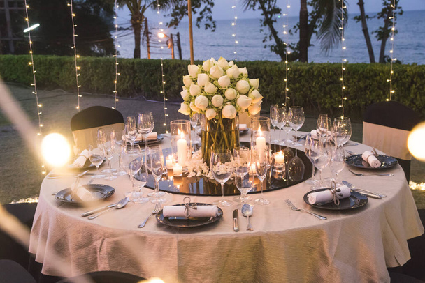Vacsora asztal beállítása esküvői ceremónia a szabadban, éjszaka a strandra néző, díszíteni lótuszvirág indiai stílusban - Fotó, kép