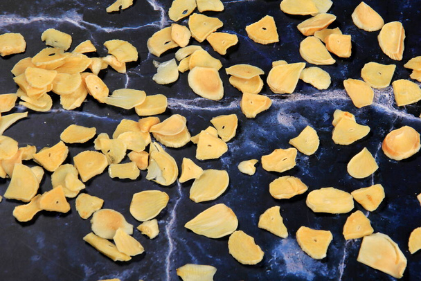 Dried garlic flakes on dark blue marble background. Dried vegetables - Photo, image