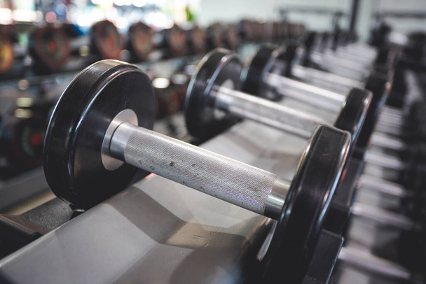 Geringes Gewicht Hantel in die Regale im Fitnesscenter gestellt, mit etwas Staub drauf - Foto, Bild