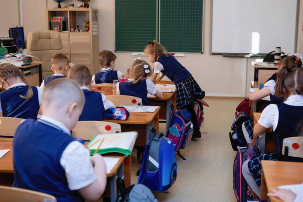 Schulkinder sitzen während des Unterrichts an ihren Schreibtischen im Klassenzimmer. Grundschulbildung. Ansicht von oben. Selektiver Fokus. - Foto, Bild