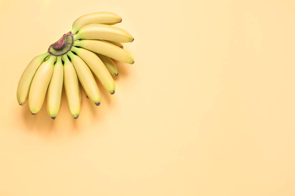 Bunch of ripe baby bananas on light orange background, top view. Space for text - Foto, afbeelding