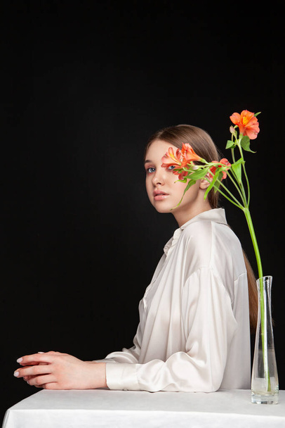 Young woman hiding face behind fresh flowers - Foto, afbeelding