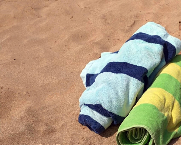 τυλιγμένα ρούχα τοποθετημένα στην αμμώδη παραλία - Φωτογραφία, εικόνα