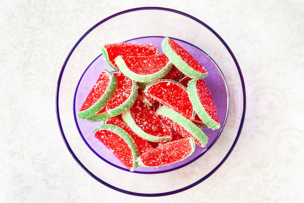 Gelee Bonbons. Draufsicht auf mit Zucker bestreute Wassermelonengelee in einer transparenten Schüssel auf hellem Hintergrund. Wassermelonenmarmelade. Selektiver weicher Fokus. Bioprodukte. - Foto, Bild