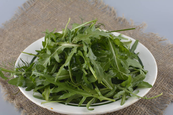 Fresh green arugula in bowl on table. Arugula rucola for salad. Close up of fresh green healthy food. Diet concept. - Fotoğraf, Görsel