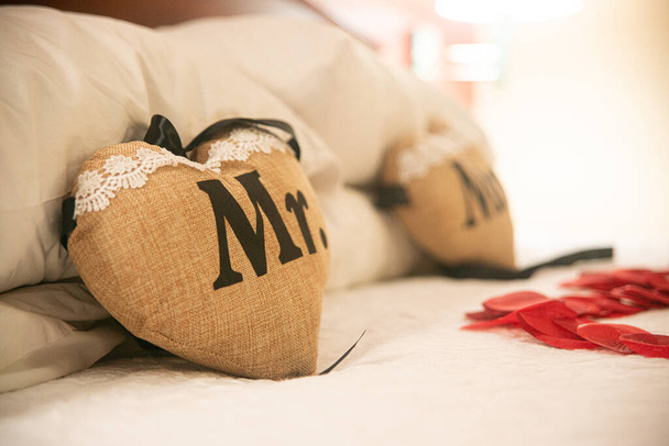 Beige Mr. & Mrs. Heart pillows with white lace and black letters on a bed - Foto, afbeelding