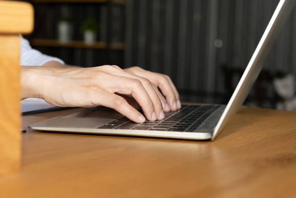 Side view and close up of young woman hands are typing on the modern laptop computer keyboard on wooden office table desktop with supplies for business and technology concept. - Photo, Image