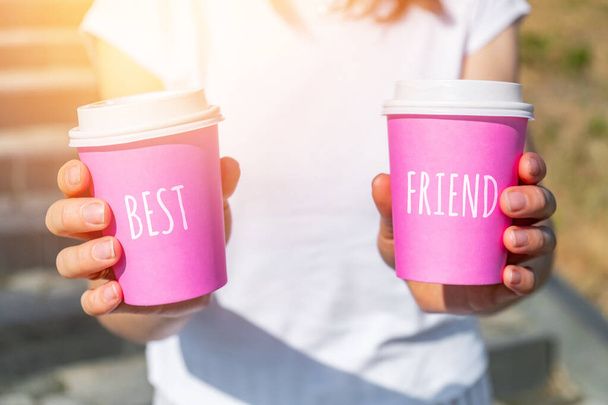 Person holding two pink disposable cups with best friend concept - 写真・画像