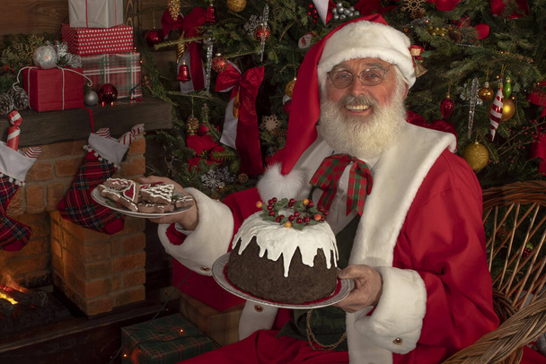 Święty Mikołaj z prawdziwą białą brodą wewnątrz domku dziennika. Dziadek gotuje, piernik, budyń na Wigilię. Starszy model z prawdziwym cosplay broda Ojciec Boże Narodzenie - Zdjęcie, obraz