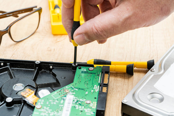 Hands of a man taking apart a broken hard disk. Technology concept. - Foto, imagen
