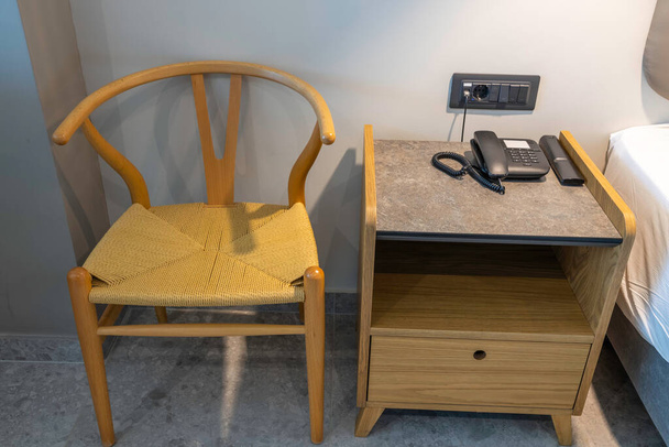 Zavřít pohled na noční stolek, židle, telefon a dálkové ovládání. Design interiéru v hotelu. Řecko.  - Fotografie, Obrázek