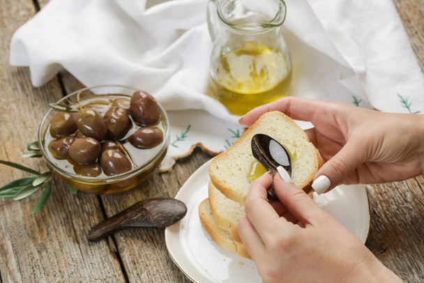 Жінка, яка має здорову закуску, оливки, оливкову олію та хліб
. - Фото, зображення