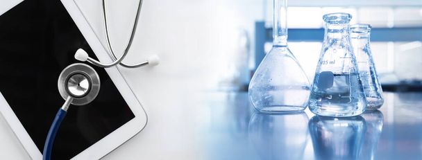 clear water in flask with stethoscope and computer tablet in diagnosis medical science lab banner background - Photo, image