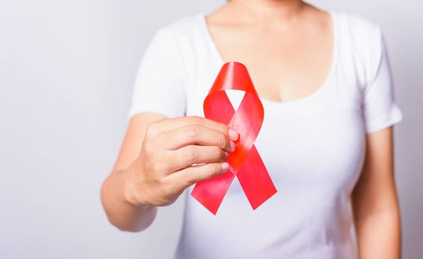 Closeup of female with red ribbon HIV AIDS on hand, World AIDS Day and medicine concept - Foto, Imagem