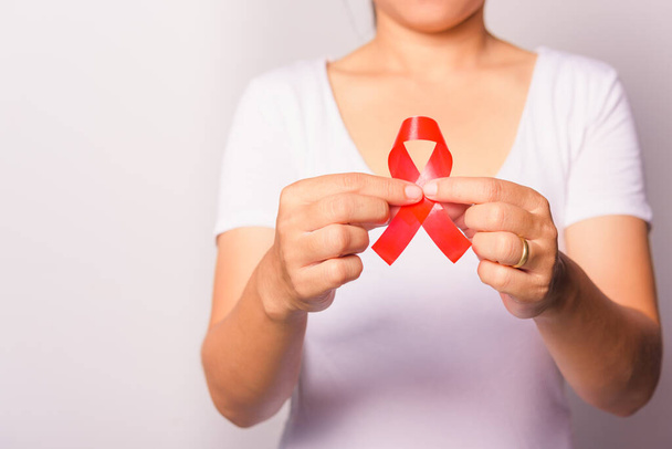 Closeup of female with red ribbon Support HIV AIDS on hands, World AIDS Day and medicine concept with copy space for use - Valokuva, kuva