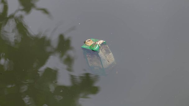 Polluted lake, milk container floating in filthy water. Water pollution photograph. - Fotó, kép