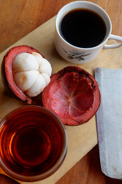 The photo is a photo of a person holding mangosteen and tea - Photo, Image